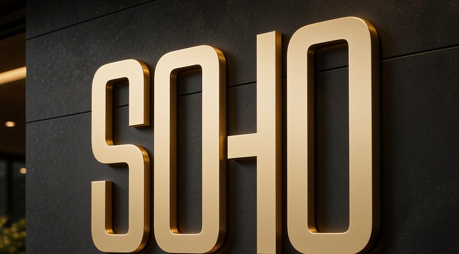 Латунная вывеска SOHO на тёмной каменной стене входной группы